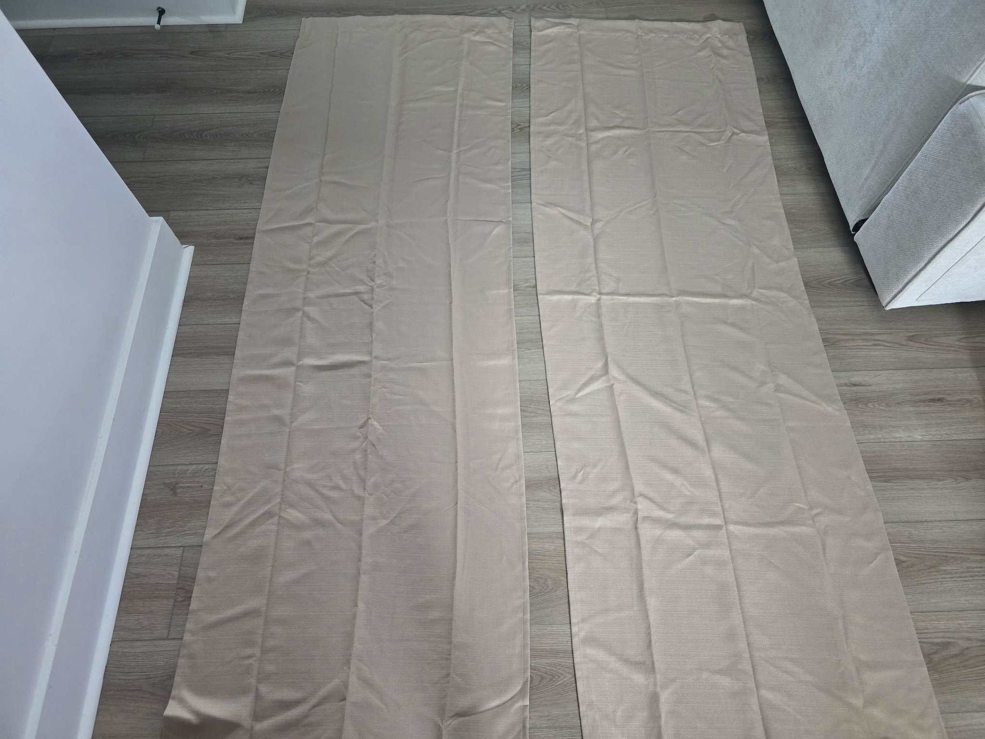 Mainstays Beige Curtains 2 panels 84x27 inches laid flat on wooden floor next to couch