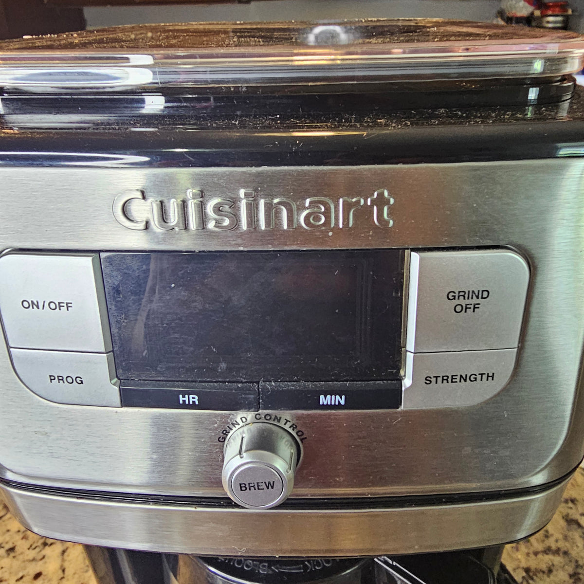 Silver Cuisinart coffee maker with digital display, buttons for settings, and a grind-off option.