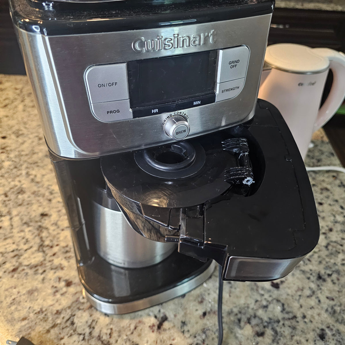 Silver and black coffee maker on a granite countertop with an open lid revealing the filter.