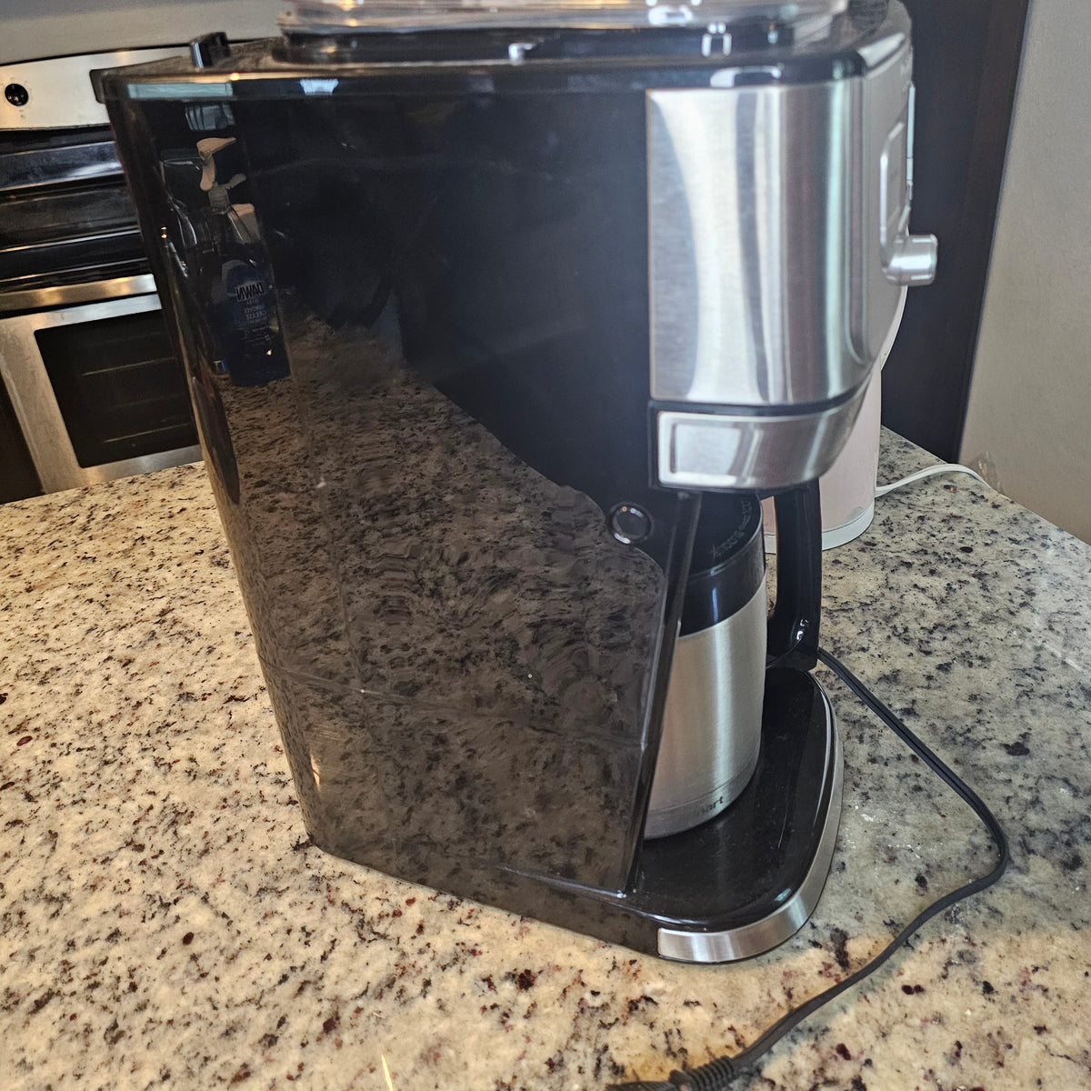 Black and silver coffee maker on a speckled granite countertop.