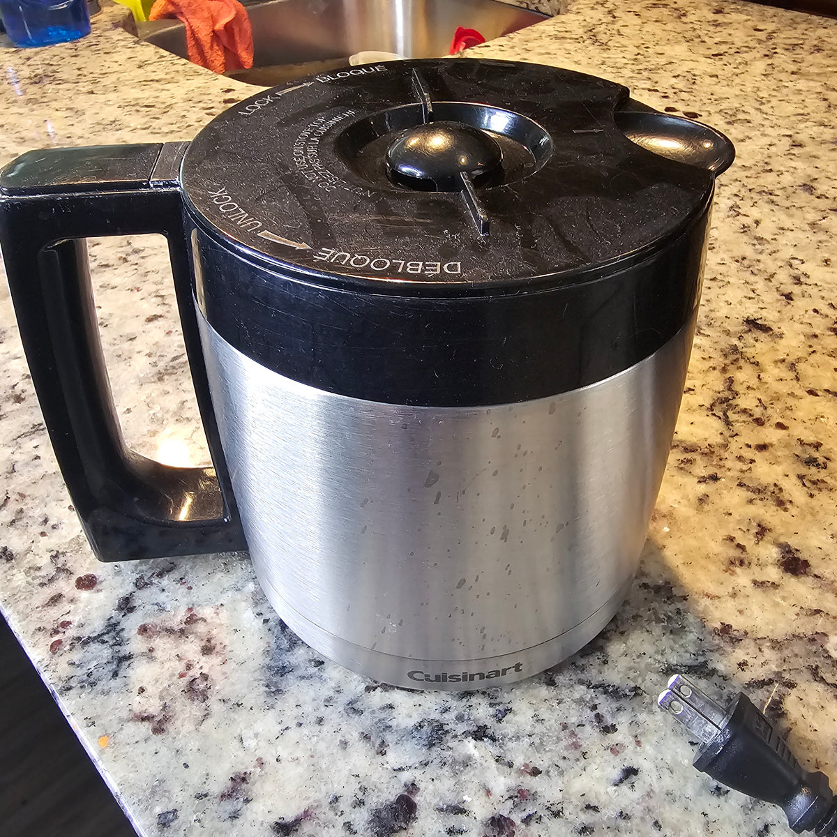 Silver and black electric kettle on a speckled countertop, with a detached black power cord.