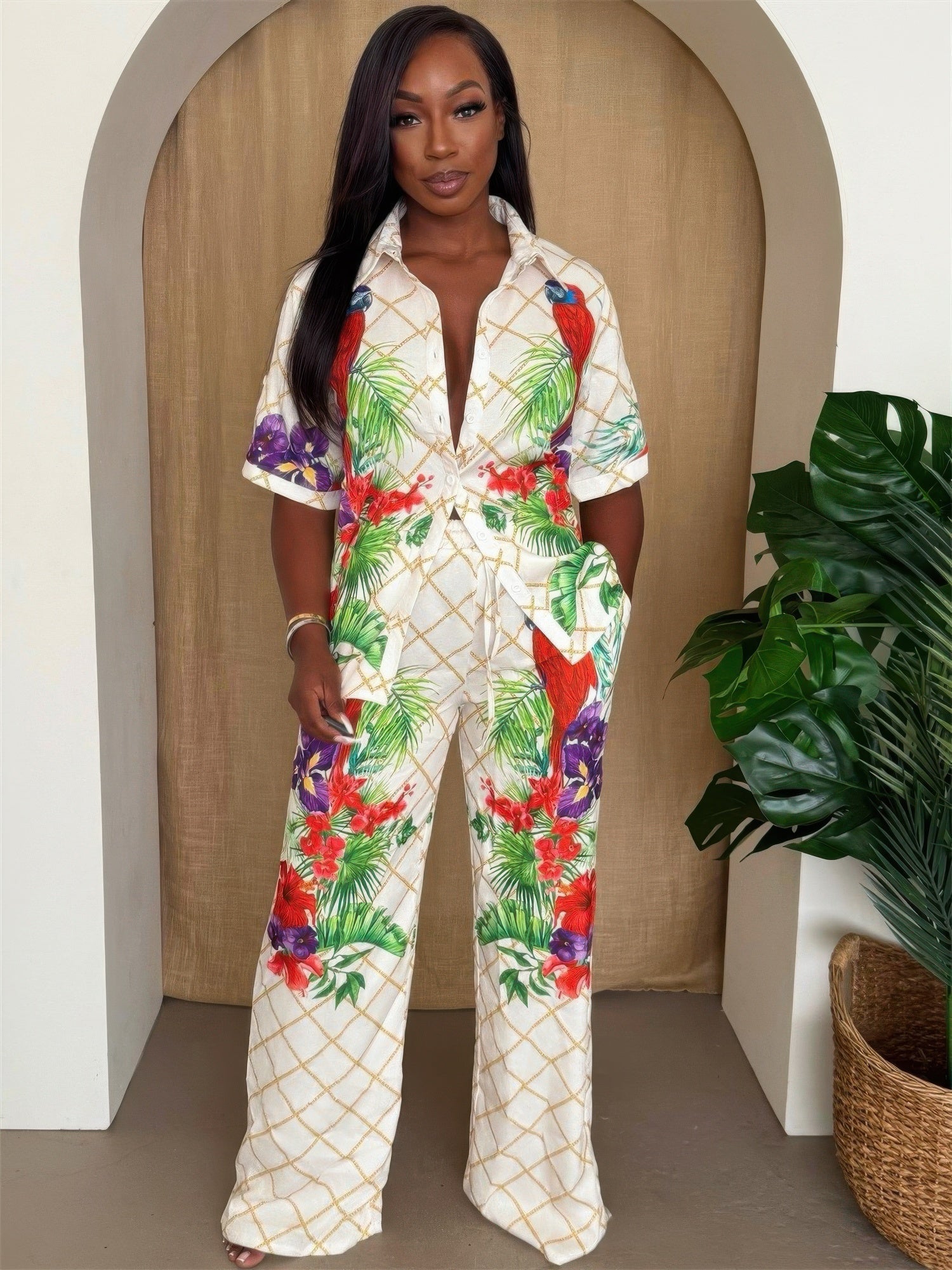 Woman wearing tropical parrot print shirt and pant set with colorful parrots and florals on cream lattice backdrop