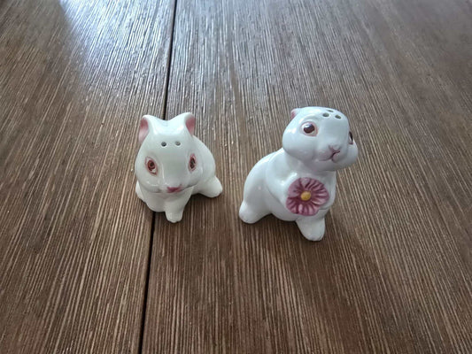 Vintage Avon 1983 ceramic bunny salt and pepper shakers with hand-painted details and flower design on wooden surface