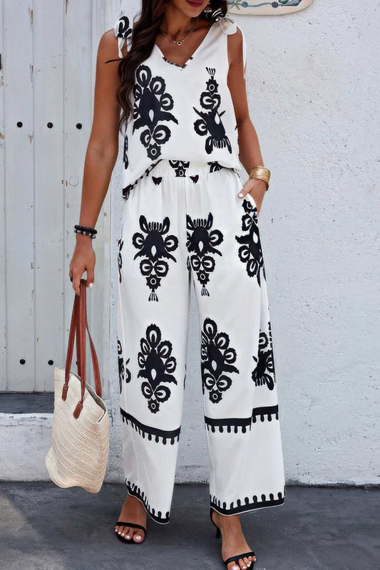 woman wearing white floral knot shoulder sleeveless elastic waist set with black pattern and carrying beige woven bag